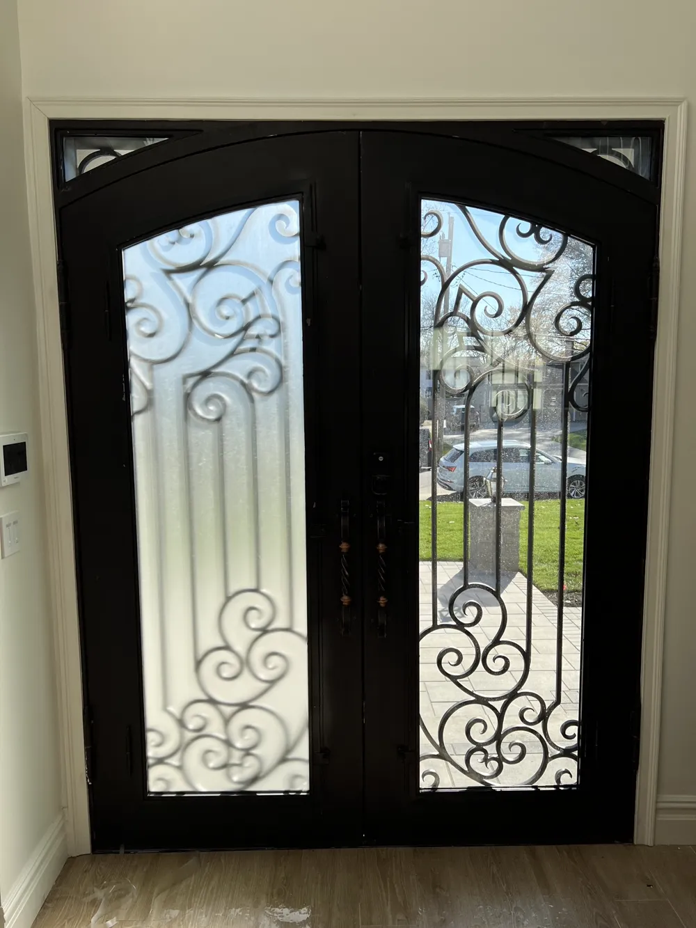 Ornate wrought-iron double-door entry with decorative security film pattern